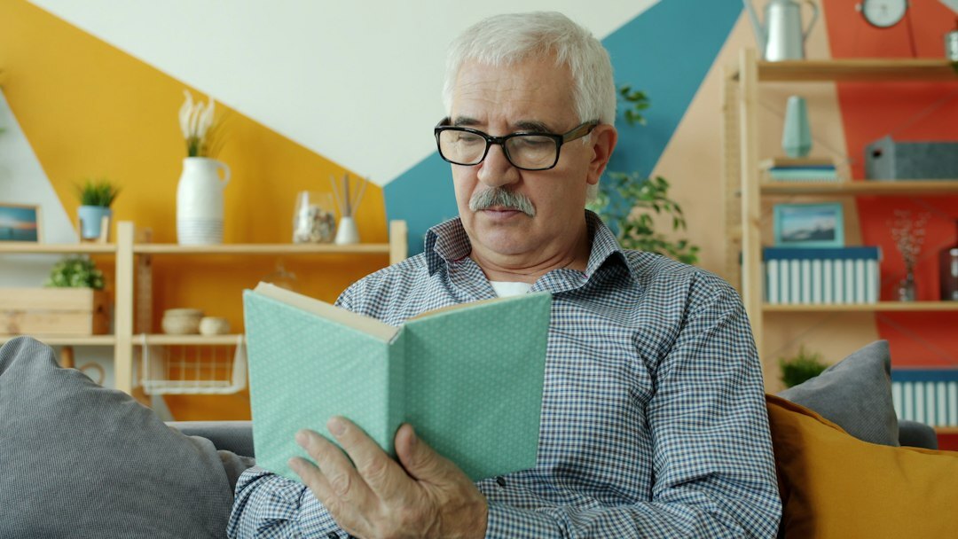 senior reading book at home
